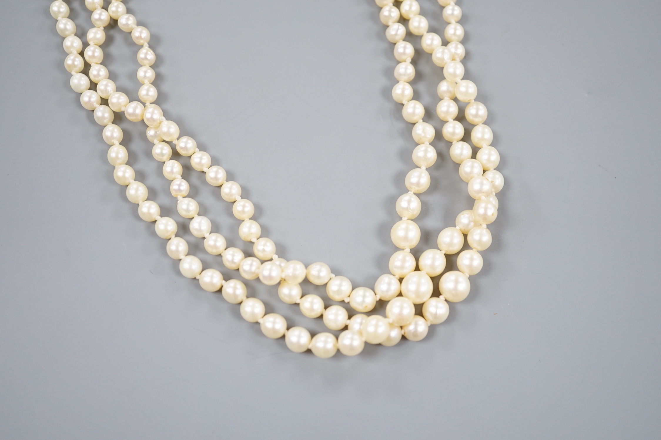 A triple strand graduated cultured pearl necklace, with yellow metal clasp, 50cm.